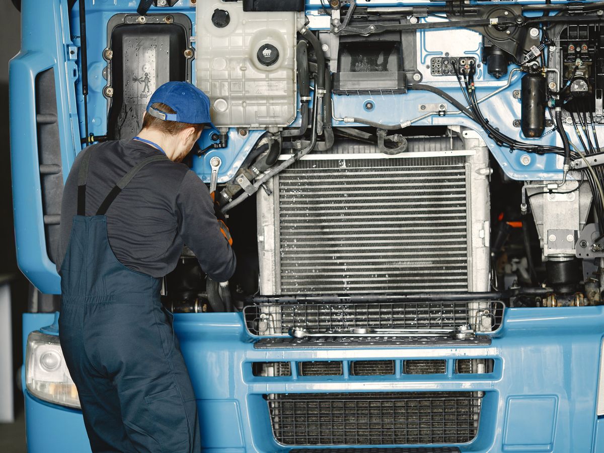Mechanic working beside the radiator of a truck with the front grille open